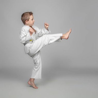 Kimonolu beyaz çocuk dövüş sanatlarında kata yapıyor..