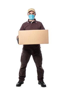 Covid-19 için maskeli teslimatçı. Elinde büyük bir paket var. Beyaz üzerine izole edilmiş. Güvenli iş ve pandemik koruma.