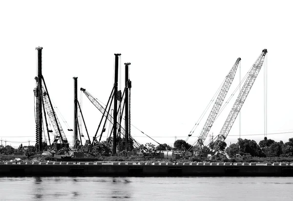 A construction site with drilling rigs and cranes seen in silhouette