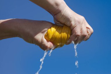 Hands drying wet cloth against blue sky clipart