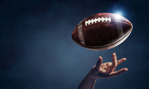 Female hand on dark background and rugby ball