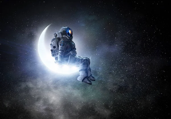 O astronauta senta-se na lua crescente. Meios mistos — Fotografia de Stock
