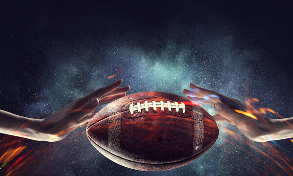 Male hand on dark background and rugby ball in palm