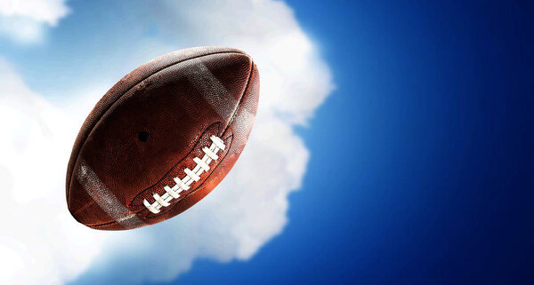 Rugby ball floating against white cloud background . Mixed media