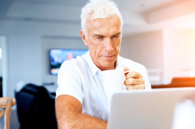 Adam evde dizüstü bilgisayarla çalışıyor.