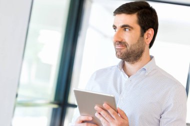 Genç yakışıklı işadamı onun touchpad ayakta kullanma office