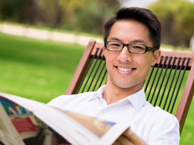 İş adamı parkta bir gazete okuyor