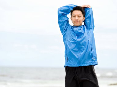 Genç adam sahilde egzersiz yaparak