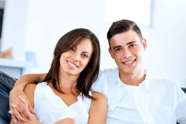 Genç çift evde otururken kameraya bakıyor