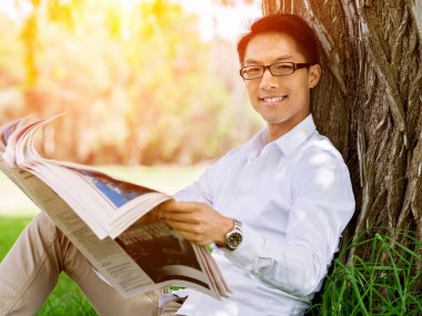 İş adamı parkta bir gazete okuyor