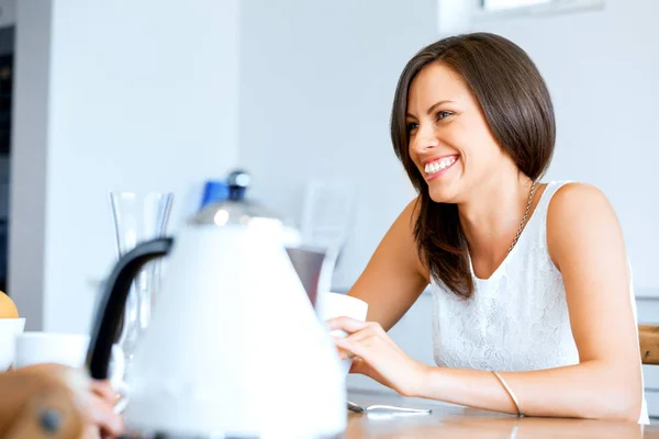Счастливая молодая женщина с чашкой чая или кофе дома — стоковое фото