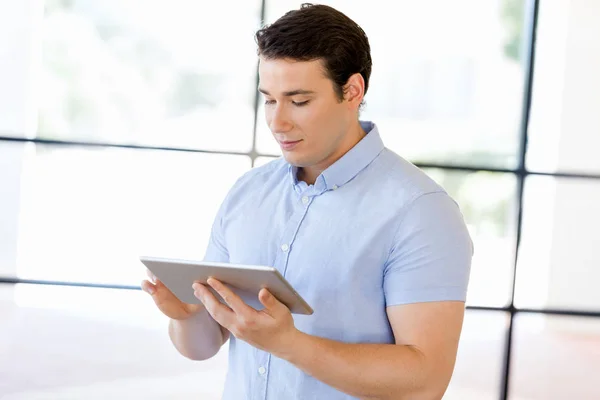 Ung snygg affärsman använder hans touchpad stående i office — Stockfoto