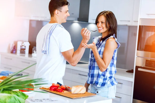 Jovem casal na cozinha degustação de alimentos — Fotografia de Stock