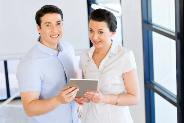 Jonge man en vrouw met touchpad staan in kantoor — Stockfoto