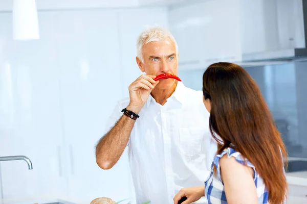 Homem segurando uma pimenta vermelha ao lado de sua cara — Fotografia de Stock