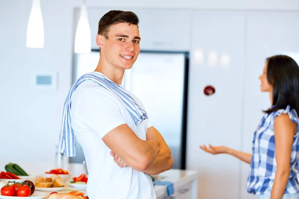 Jovem de pé na cozinha e sorrindo — Fotografia de Stock