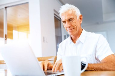 Adam evde dizüstü bilgisayarla çalışıyor.