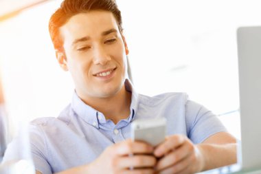 Kendine güvenen genç adam akıllı rahat kıyafet telefon tutarak