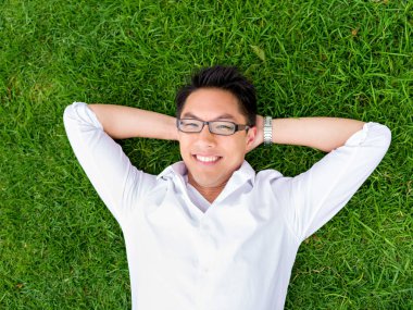 Ppretty genç adam beyaz gömlekli bir çim üzerinde rahatlatıcı