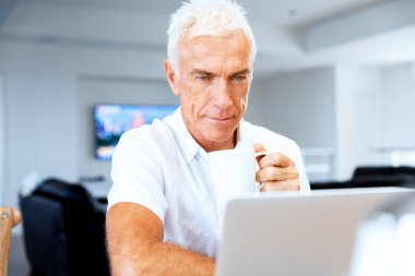 Adam evde dizüstü bilgisayarla çalışıyor.