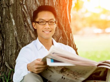 İş adamı parkta bir gazete okuyor