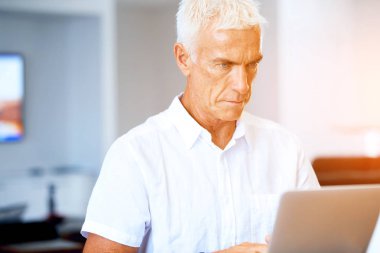 Adam evde dizüstü bilgisayarla çalışıyor.