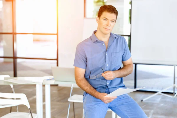 Junger Geschäftsmann sitzt auf einem Hocker im Büro — Stockfoto