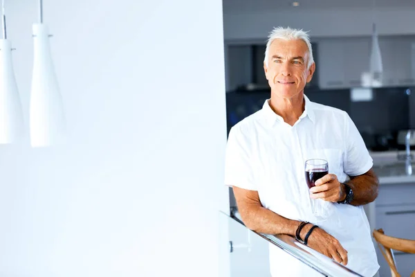 Senior man met een glas wijn binnenshuis te houden — Stockfoto