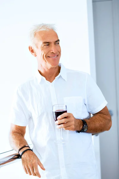 Старший мужчина с бокалом вина в помещении — стоковое фото
