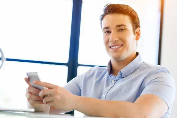 Självsäker ung man i smart fritidskläder som håller telefonen — Stockfoto