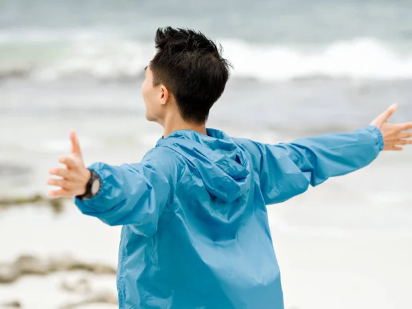 Ung man med utsträckta armar på stranden — Stockfoto