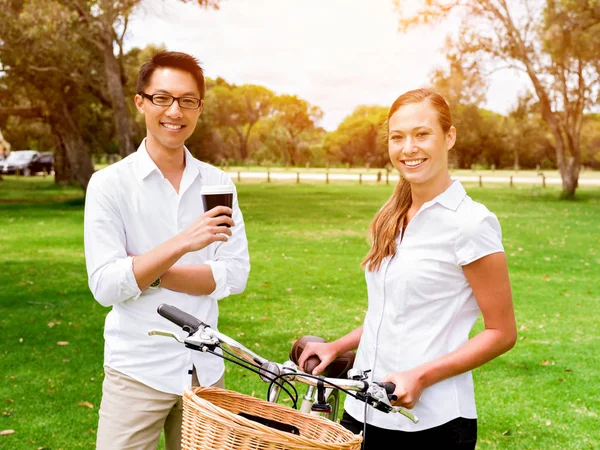 Портрет улыбающейся пары, стоящей в парке и разговаривающей на велосипеде — стоковое фото
