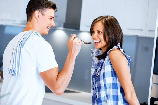 Jovem casal na cozinha degustação de alimentos — Fotografia de Stock