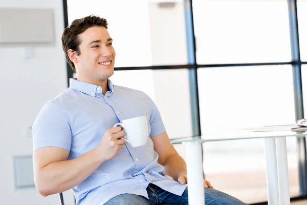 Young businessman in office with a mug — Stock Photo, Image