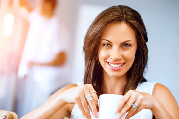 Gelukkige jonge vrouw met kopje thee of koffie — Stockfoto