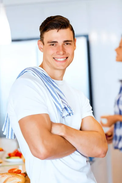 Молодий чоловік стоїть на кухні і посміхається — стокове фото