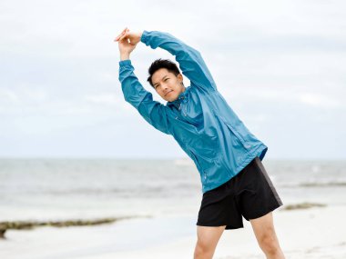 Genç adam sahilde egzersiz yaparak