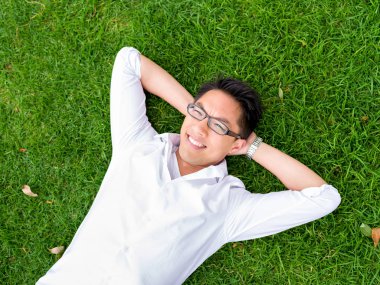 Ppretty genç adam beyaz gömlekli bir çim üzerinde rahatlatıcı