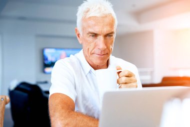 Adam evde dizüstü bilgisayarla çalışıyor.