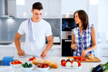 Genç çift evde birlikte yemek pişiriyor.