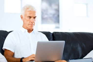 Adam evde dizüstü bilgisayarla çalışıyor.