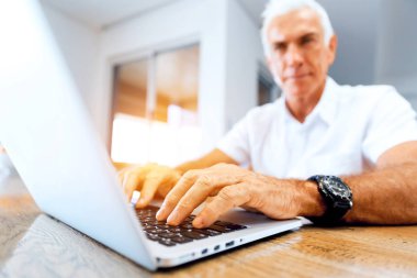 Adam evde dizüstü bilgisayarla çalışıyor.