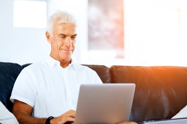 Adam evde dizüstü bilgisayarla çalışıyor.