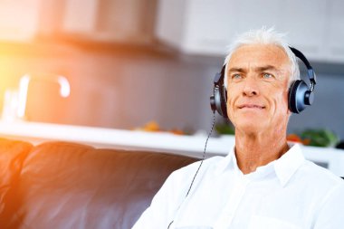 Oturma odasında müzik dinlerken kulaklık ile yakışıklı gri saçlı komuta sizde