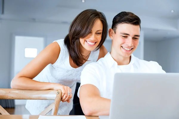 Felice coppia moderna che lavora sul computer portatile a casa — Foto Stock