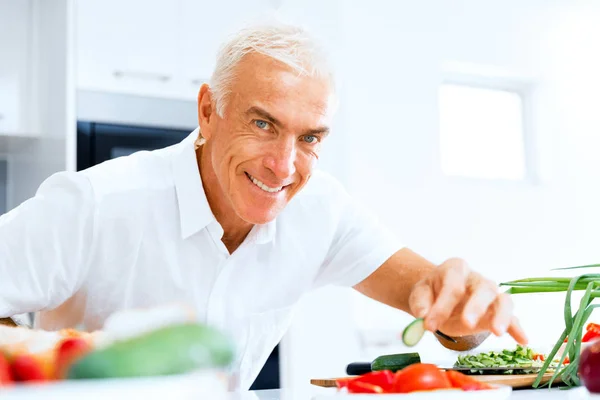 Portrait of a smart senior man cooking in kitchen — Stock Photo, Image