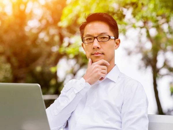 Jonge zakenman met behulp van laptop zittend buitenshuis — Stockfoto