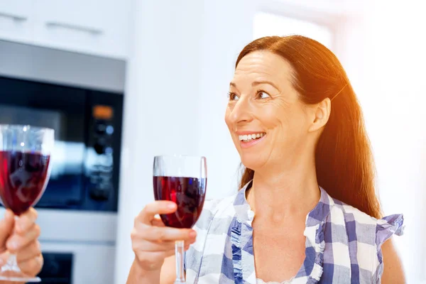 Donna anziana con in mano un bicchiere di vino in casa — Foto Stock