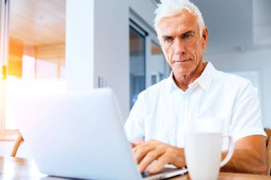 Adam evde dizüstü bilgisayarla çalışıyor.