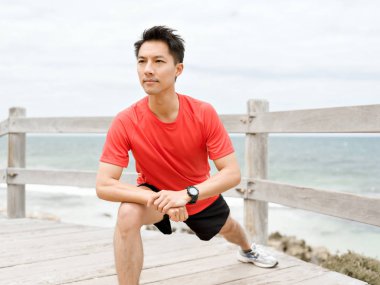 Genç adam sahilde egzersiz yaparak